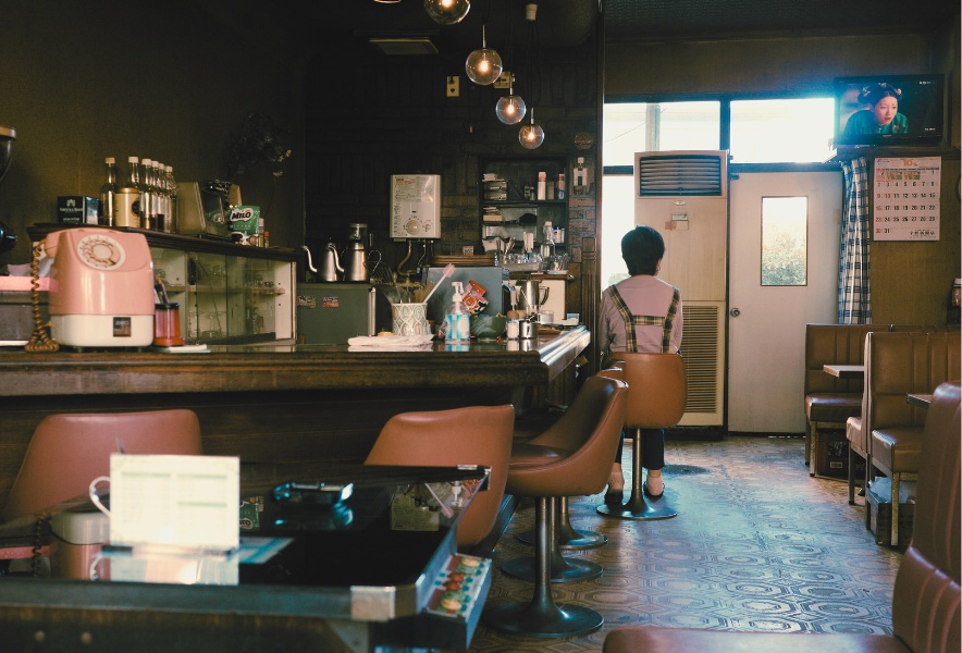 名古屋市千種区にある喫茶らんのカウンター席と店内全景。奥のテレビと　店主の後ろ姿が残る風景
