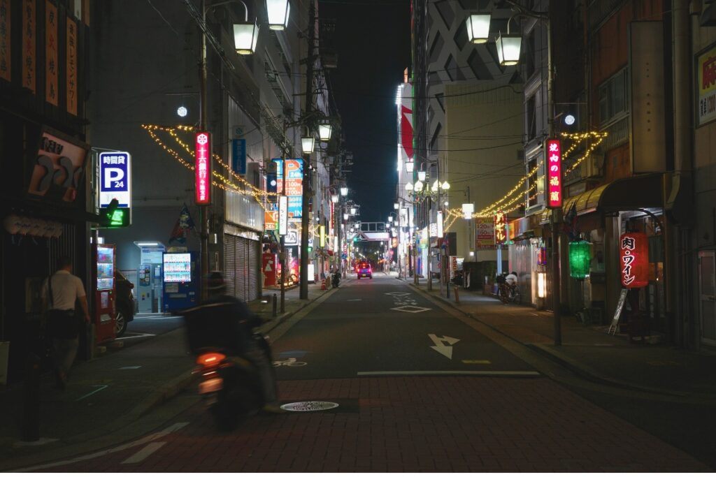 ネオンと街灯に照らされた名古屋・今池の夜の通り。新旧の店が並び、ごちゃまぜの魅力が漂う。