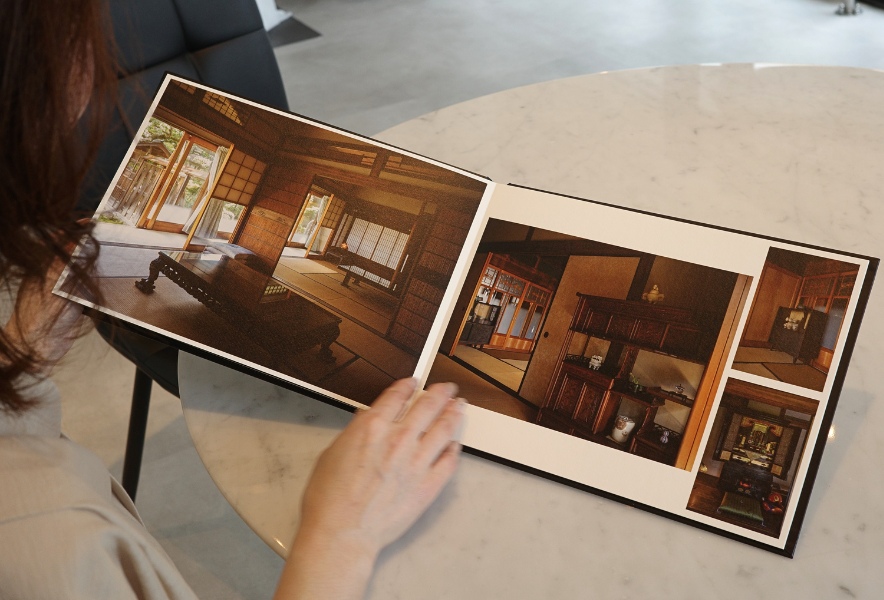 モナミ写真館で制作された写真アルバム。壊される前の日本家屋を撮影した作品を手に取る風景。