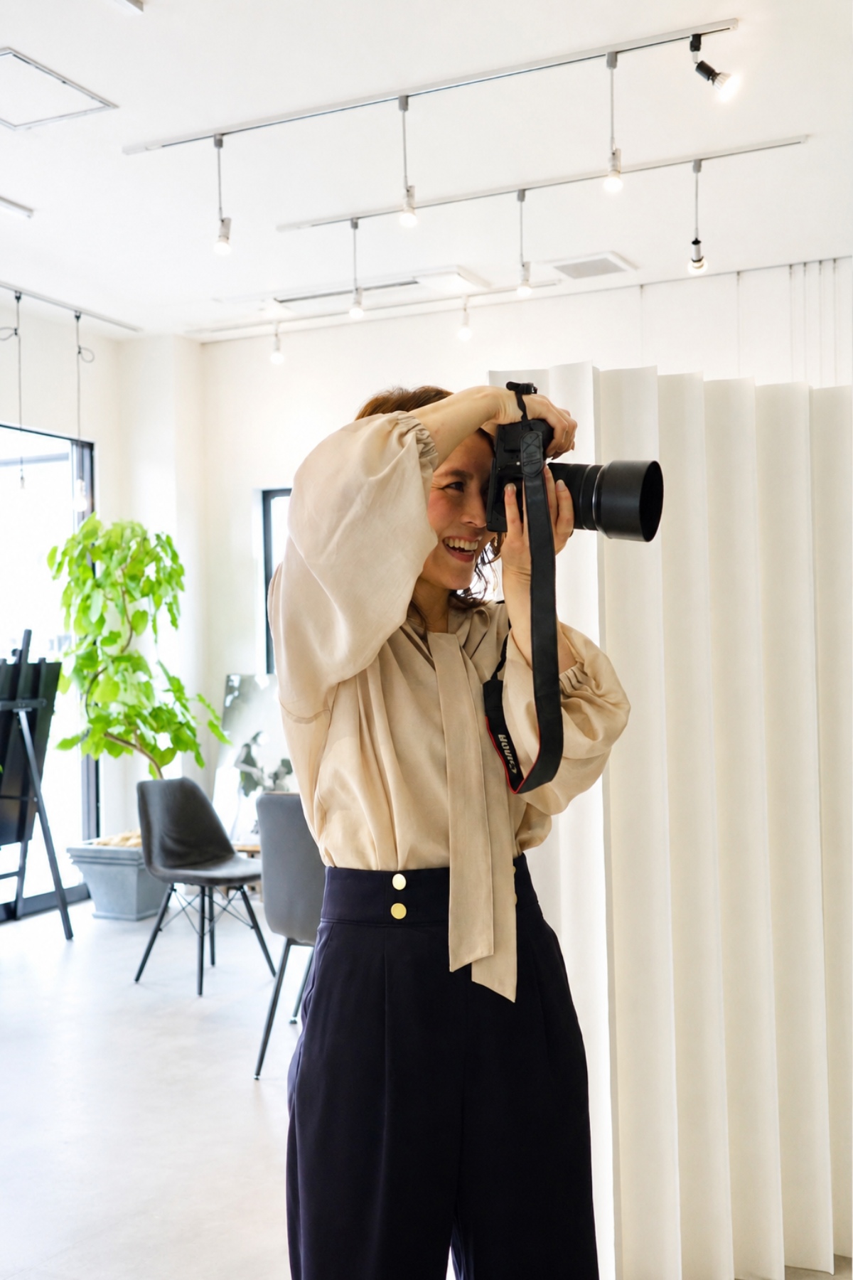 名古屋・大曽根のモナミ写真館でカメラを構える兵藤ゆきえさん。自然光が差し込むスタジオでの撮影風景。