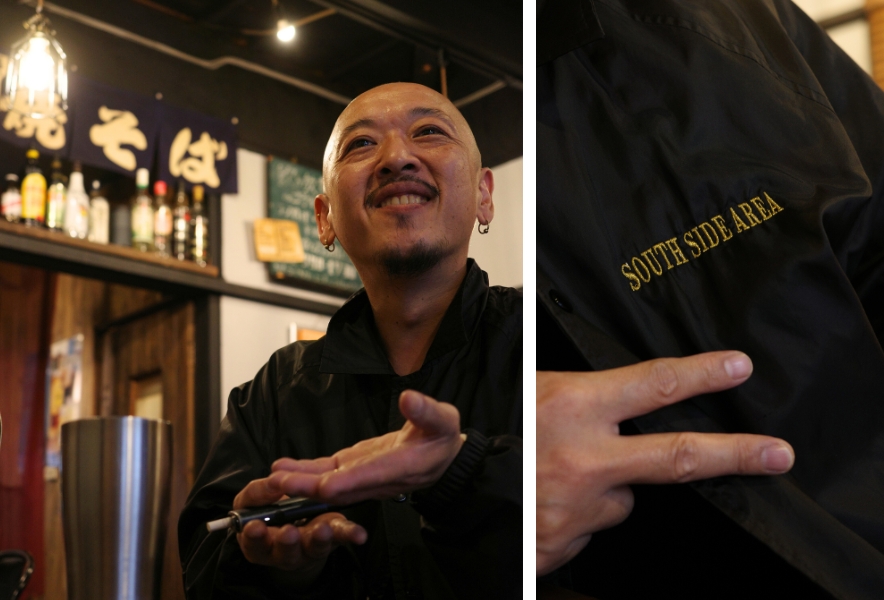 金山南の「KING焼きそば」で話す羽鳥浩二(King Papa)さん。胸元には“SOUTH SIDE AREA”と刺繍されたジャケット。金山の“南側”を象徴するように、朗らかな笑顔と手の動きが印象的。