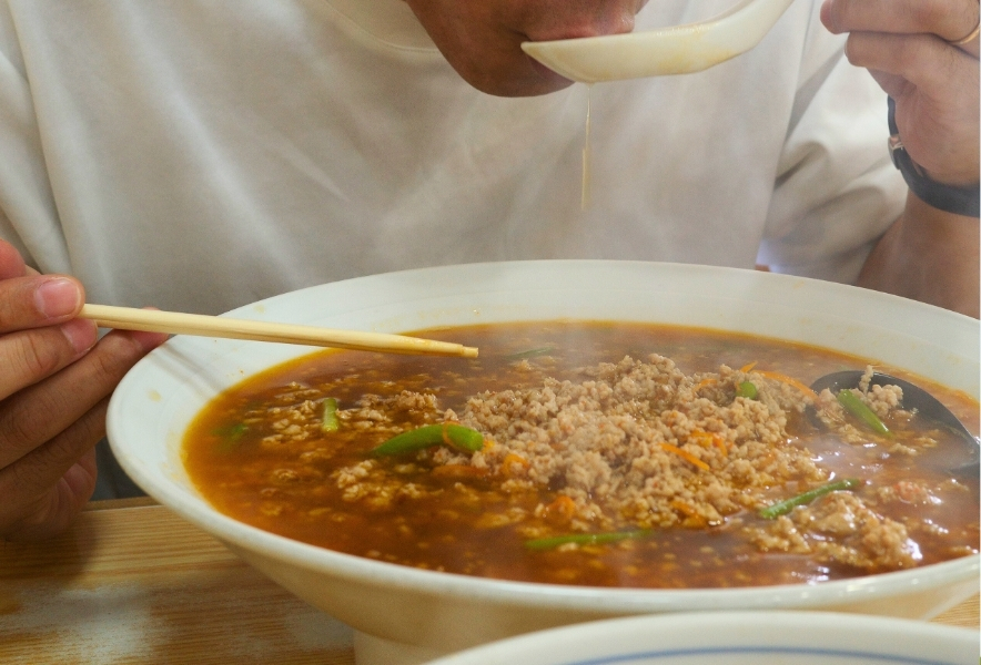 名古屋・千種区の人気店「パンダらーめん」で台湾ラーメンを食べる様子。たっぷりのひき肉と唐辛子がのった名古屋名物の一杯。