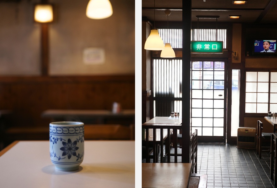 湯のみと木のテーブル、静かな店内の昼と店内入口の非常口表示|仲田本通 めん処 森川屋