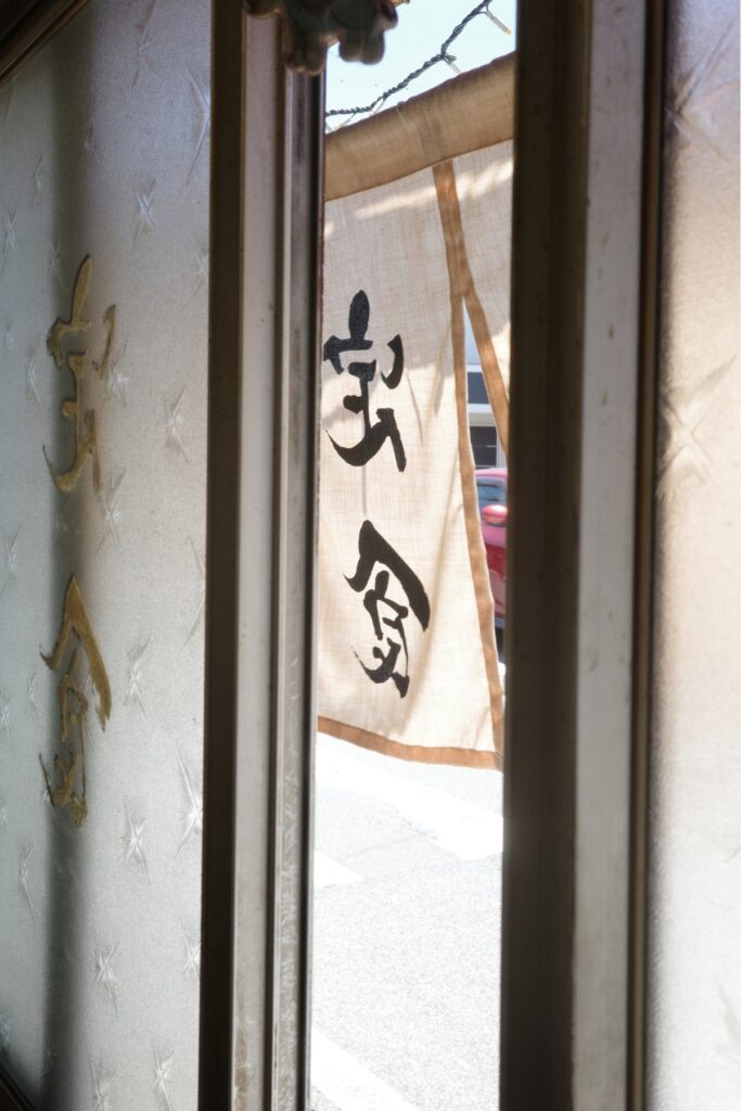 店内から見たどんぶり亭の暖簾。柔らかな光が差し込む入口の風景