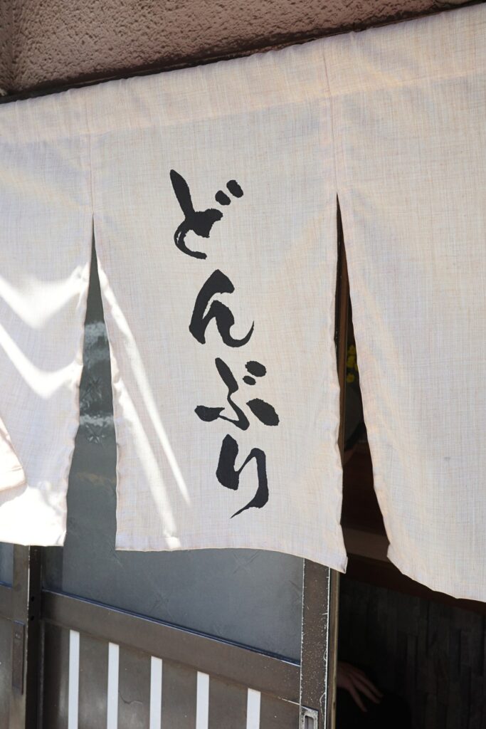 「どんぶり亭」と書かれた暖簾。名工大近くで長年親しまれた定食屋の入口